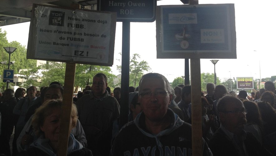 Deux supporters brandissent des pancartes avec des slogans anti-fusion