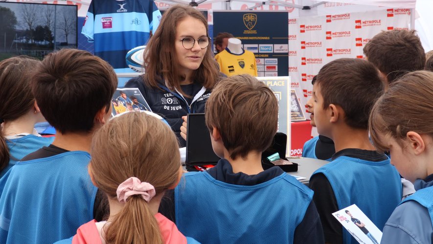Alycia Christiaens, avec devant elle, sa médaille de bronze glanée, il y a deux semaines à la Coupe du monde à VII, et au premier plan, des enfants qui écoute le récit de ses exploits