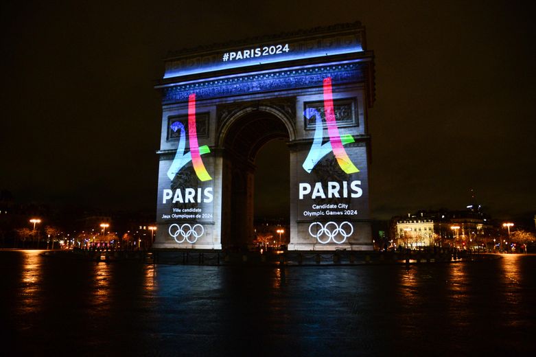L’Arc de Triomphe illuminé avec les anneaux olympiques et le logo de Paris 2024 : avant la frénésie, le calme règne, à quelques jours de l’ouverture des Jeux.
